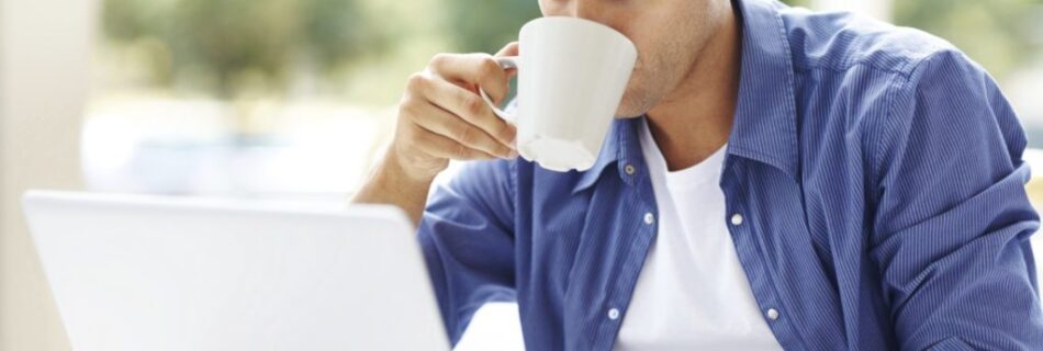 Young man drinking coffee while using at laptop