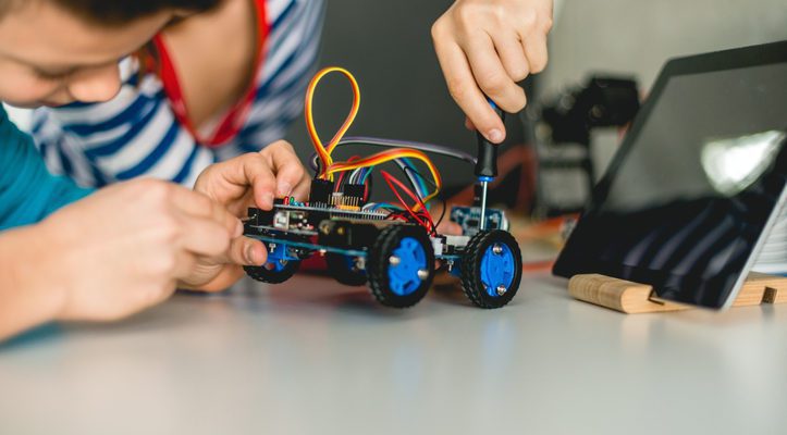 Two kids playing with a lego robotic toy