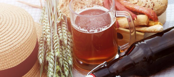 A mug of fresh craft beer without foam,a glass beer bottle with a bugle stopper, wheat, smoked sausages and bread in the open air during the day.Brewing.German-style.International