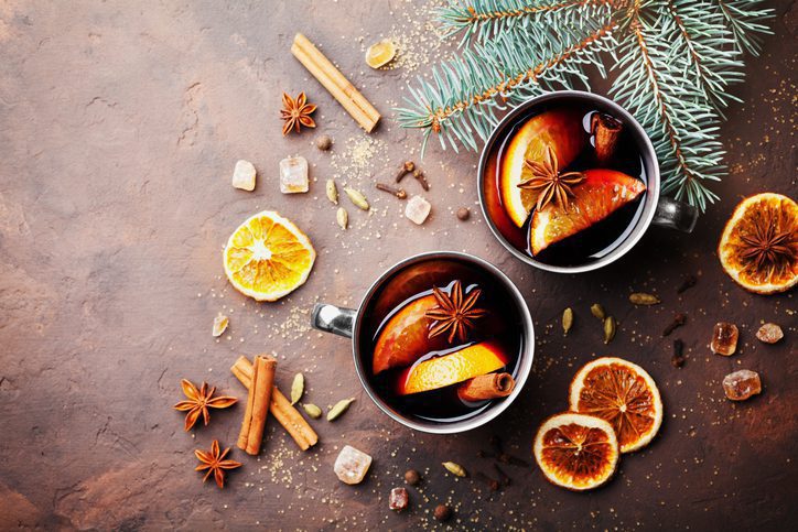 Two cups of christmas mulled wine or gluhwein with spices and orange slices on rustic table top view. Traditional drink on winter holiday. Flat lay.