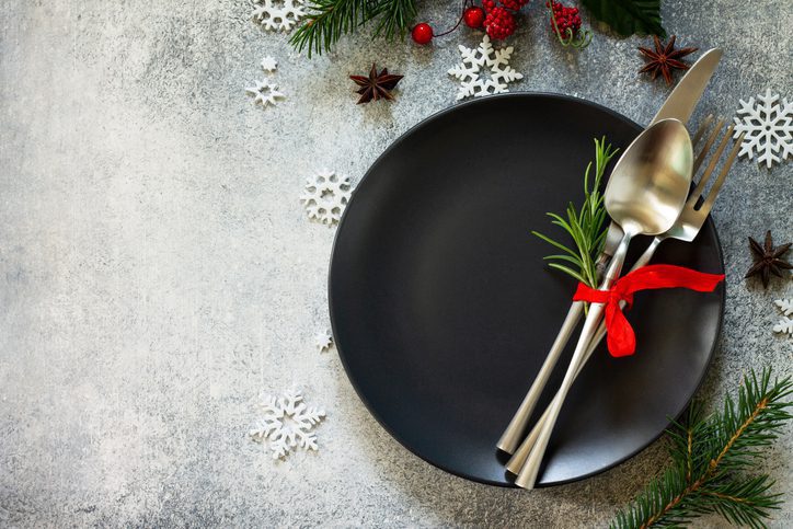 Christmas background. Christmas decoration table. Festive black plate and cutlery with Christmas decor on retro festive table. Top view flat lay. Free space for your text.