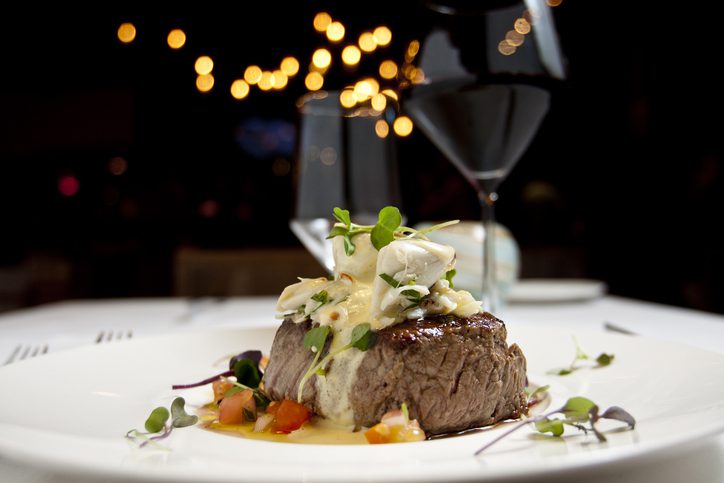 Dish of filet mignon and vegetables with glass of red wine