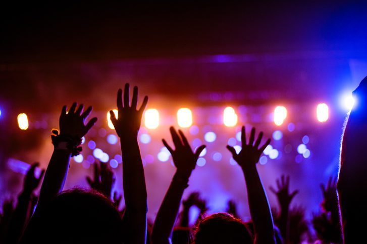 Concert showing a crowd with their hands up in the air