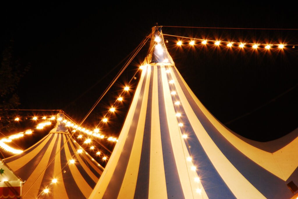 Striped carnival tent at night with string lights 