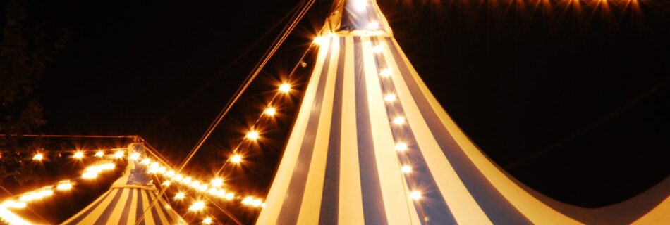 Striped carnival tent at night with string lights