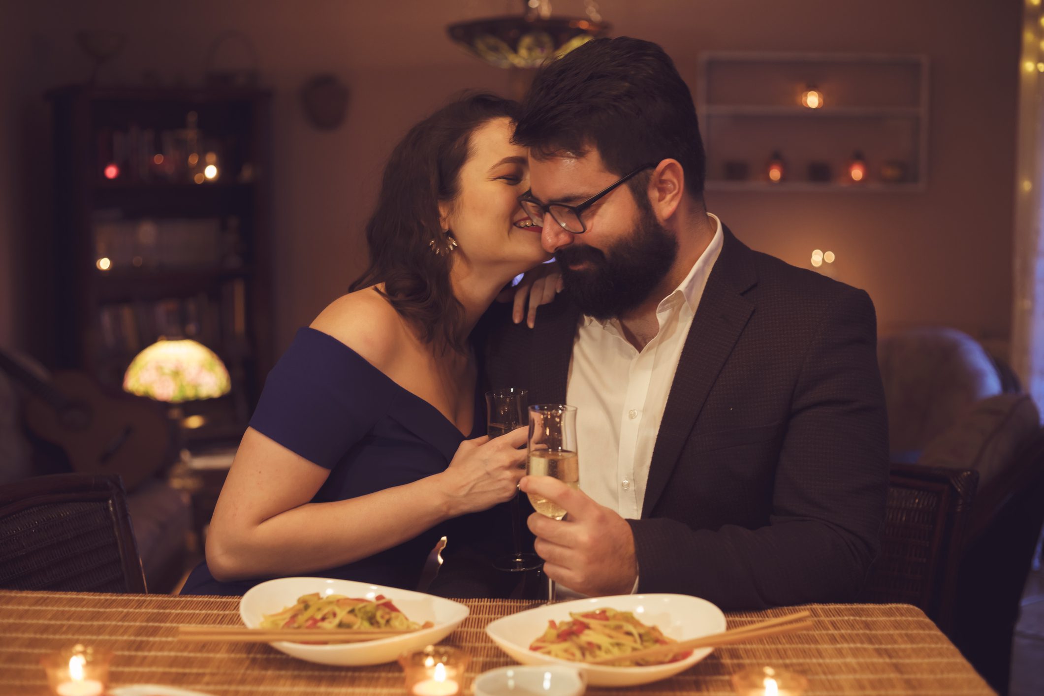 Two people on a romantic date with pasta in front of them.